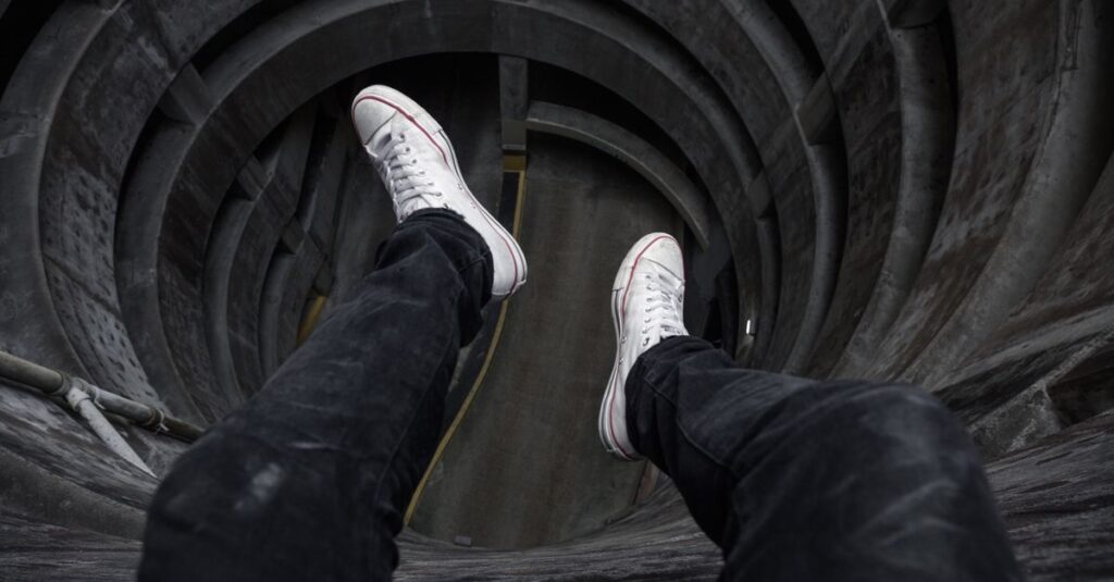 Como Enfrentar o Medo de Morrer e Viver com Coragem 2 View from above looking down into a circular structure with legs in black jeans and white shoes.