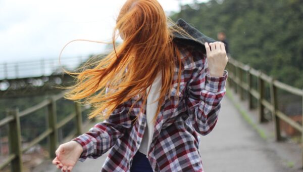 Portrait of a redhead woman outdoors with hair blowing in the wind.