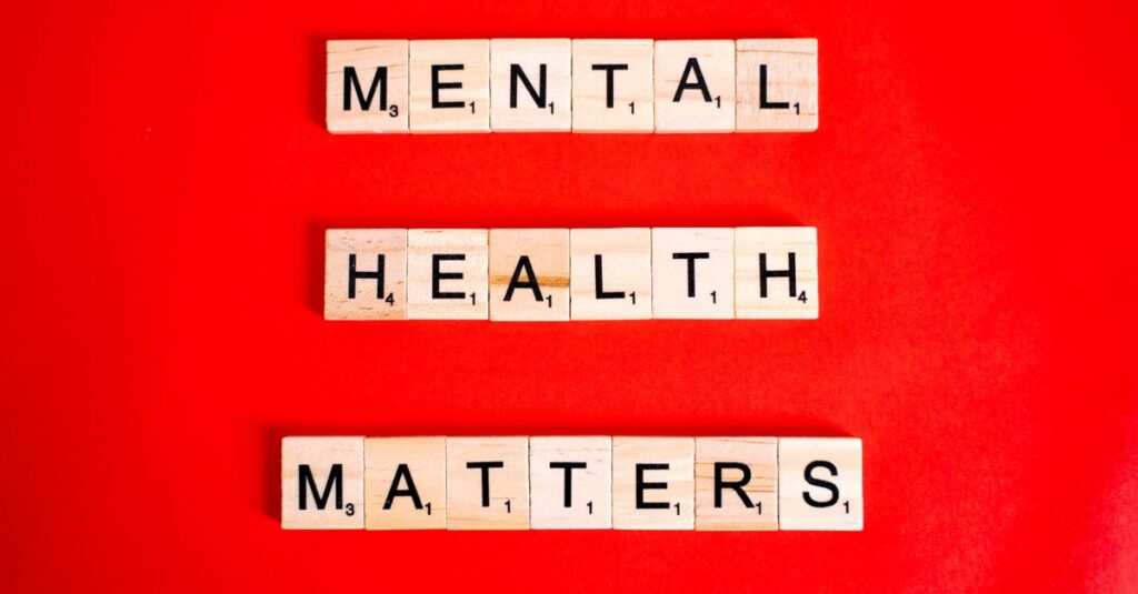 Wooden tiles spelling 'Mental Health Matters' on a vivid red background.