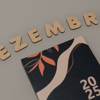 A minimalist 2025 calendar with cork letters spelling 'DEZEMBRO' on a neutral background.