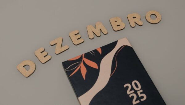 A minimalist 2025 calendar with cork letters spelling 'DEZEMBRO' on a neutral background.