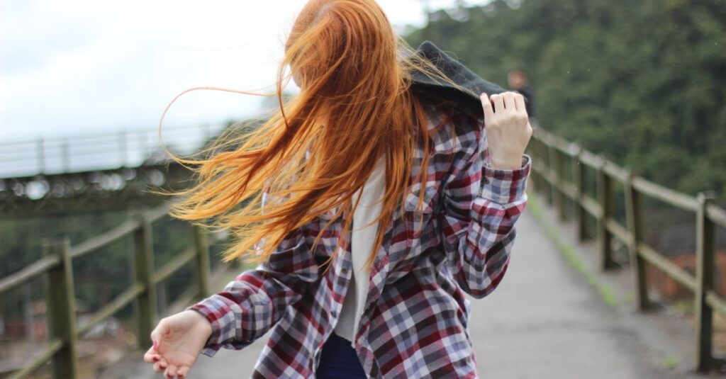 Portrait of a redhead woman outdoors with hair blowing in the wind.