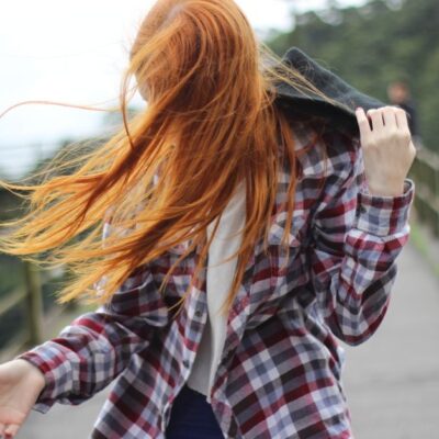 Portrait of a redhead woman outdoors with hair blowing in the wind.