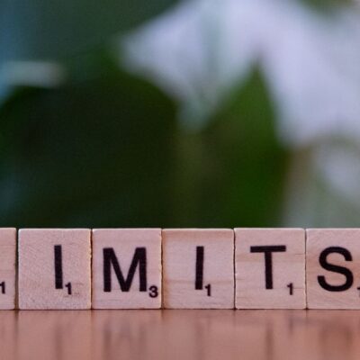 Wooden letter tiles forming the word 'LIMITS' on a wooden table.