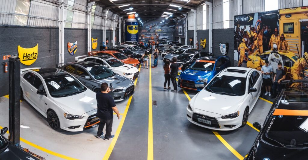 A vibrant scene of a car enthusiast gathering at Vila Nair, showcasing a variety of vehicles indoors.