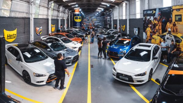 A vibrant scene of a car enthusiast gathering at Vila Nair, showcasing a variety of vehicles indoors.
