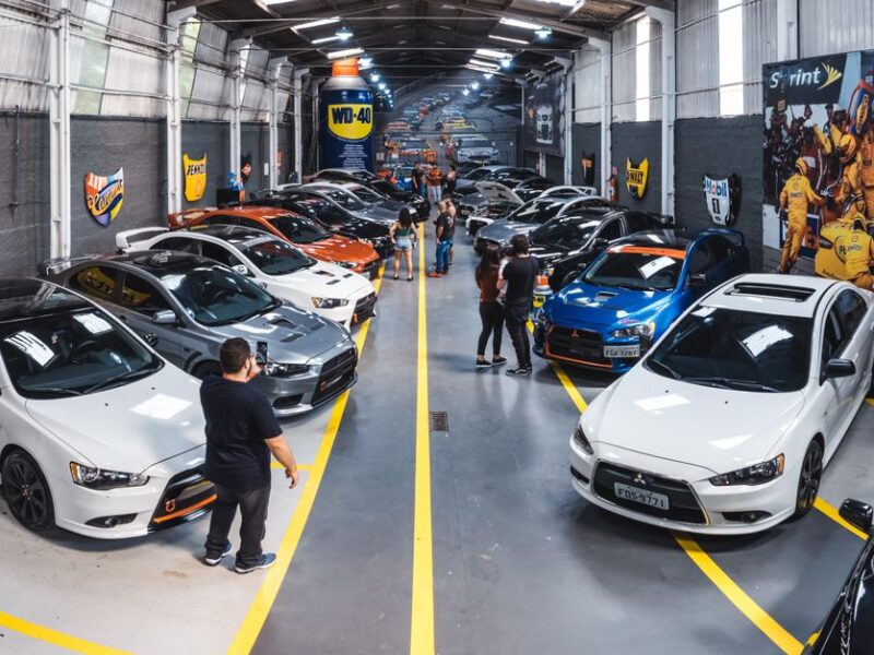 A vibrant scene of a car enthusiast gathering at Vila Nair, showcasing a variety of vehicles indoors.
