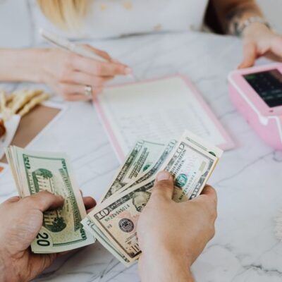Two people handling cash and budgeting with a calculator and notebook at a table.