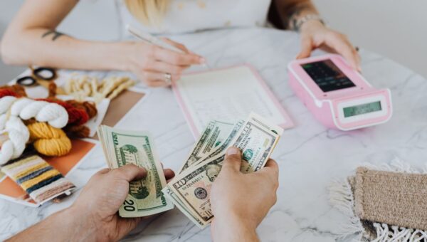 Two people handling cash and budgeting with a calculator and notebook at a table.