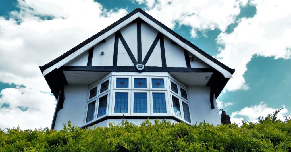 Como a Terapia de Casal Pode Fortalecer Seu Relacionamento 2 Tudor-style house facade with a bay window against a vibrant sky and greenery.