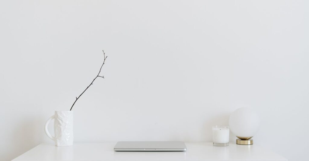 A clean, minimalistic workspace featuring a white desk, laptop, and decorative items, perfect for modern design inspiration.