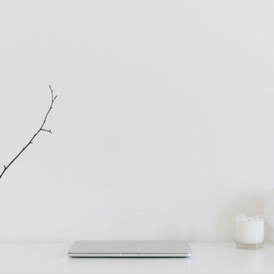 A clean, minimalistic workspace featuring a white desk, laptop, and decorative items, perfect for modern design inspiration.