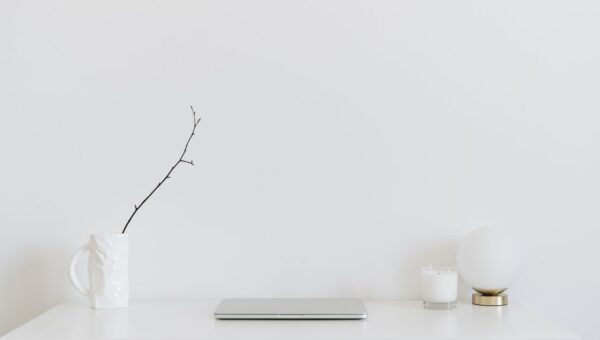 A clean, minimalistic workspace featuring a white desk, laptop, and decorative items, perfect for modern design inspiration.