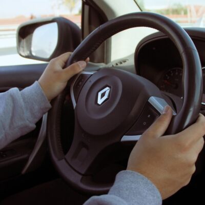 Close-up of hands on steering wheel while driving through Mexico in daylight.