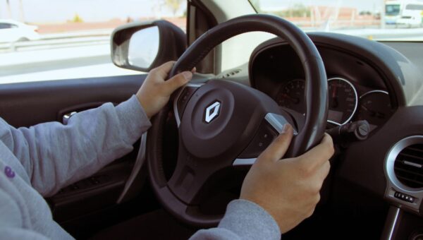 Close-up of hands on steering wheel while driving through Mexico in daylight.