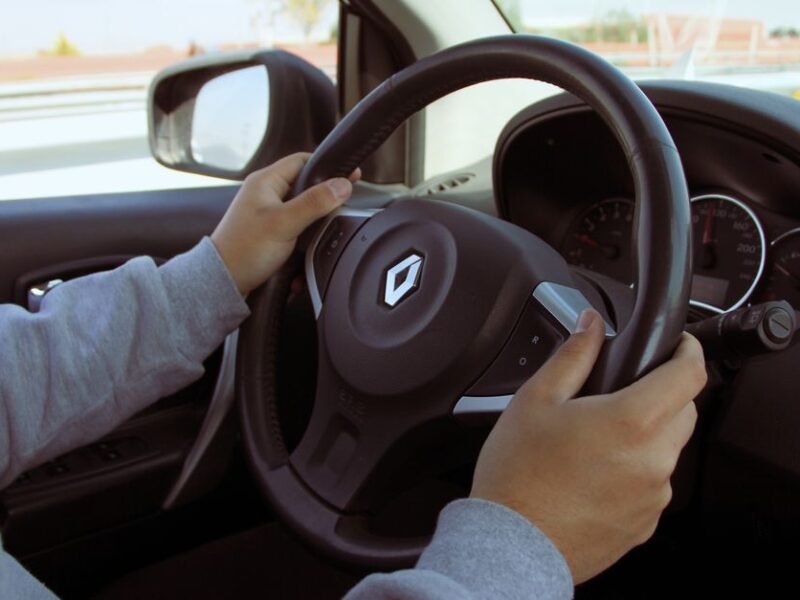 Close-up of hands on steering wheel while driving through Mexico in daylight.