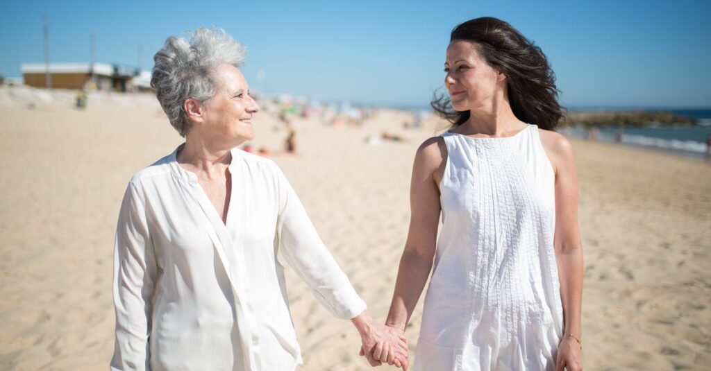 Joyful moment of a mother and daughter holding hands on a sunny beach in Portugal.