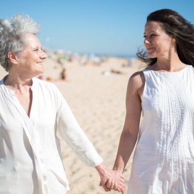 Joyful moment of a mother and daughter holding hands on a sunny beach in Portugal.