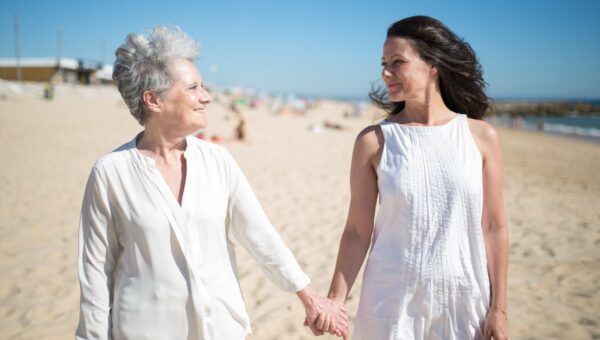 Joyful moment of a mother and daughter holding hands on a sunny beach in Portugal.