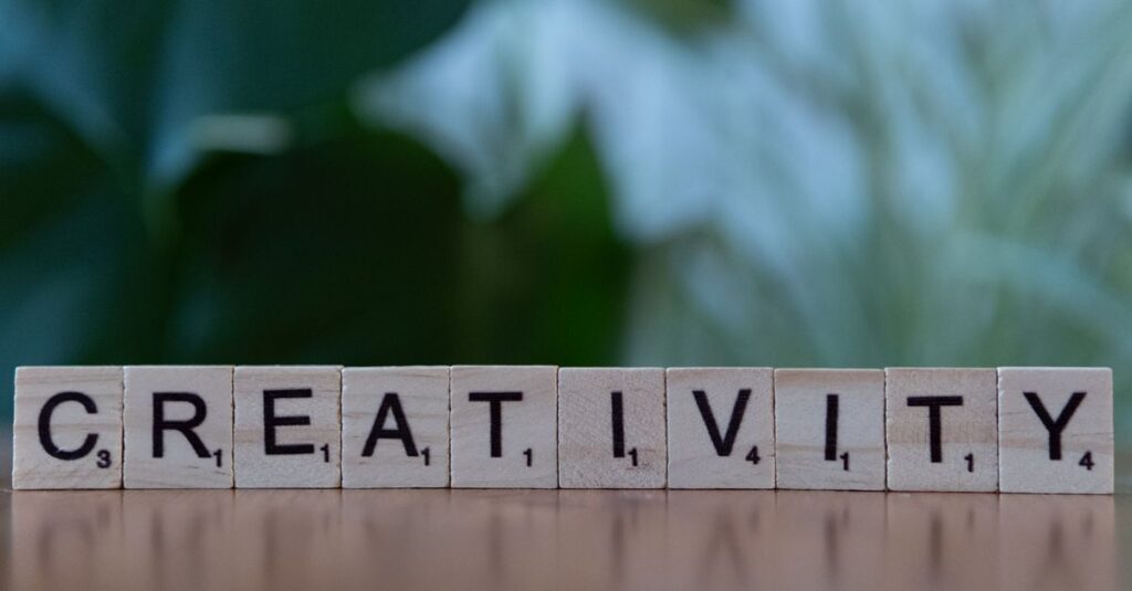 Scrabble tiles spelling 'CREATIVITY' with a blurred green background.