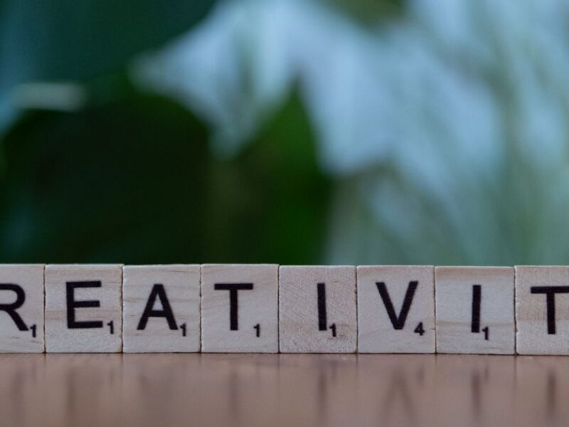 Scrabble tiles spelling 'CREATIVITY' with a blurred green background.