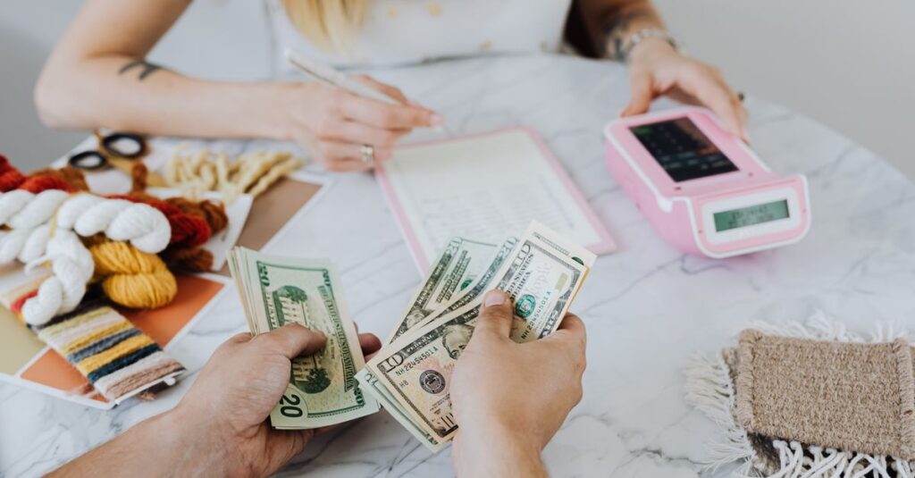 Como Organizar suas Finanças Pessoais com Dicas Práticas 2 Two people handling cash and budgeting with a calculator and notebook at a table.