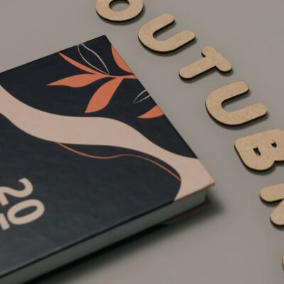 Minimalist flat lay featuring a 2025 planner and cut-out letters spelling 'OUTUBRO'.