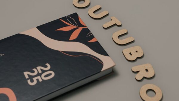 Minimalist flat lay featuring a 2025 planner and cut-out letters spelling 'OUTUBRO'.