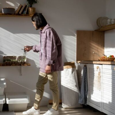 Man in casual wear tending to indoor plants in a sunlit kitchen.