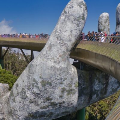The iconic Golden Bridge with giant hand sculptures at Ba Na Hills, Vietnam, under a clear blue sky.