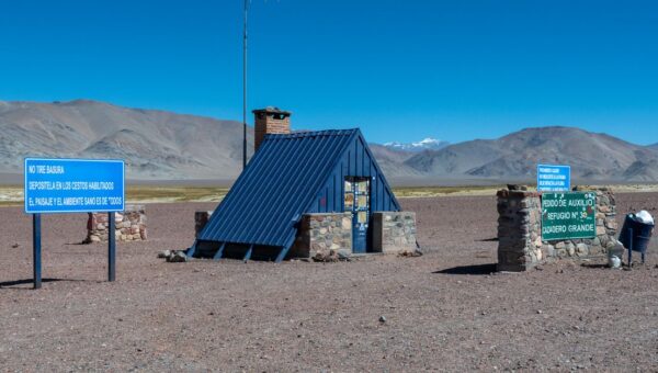 Stone shelter and signs against Andes Mountains in Catamarca, Argentina.