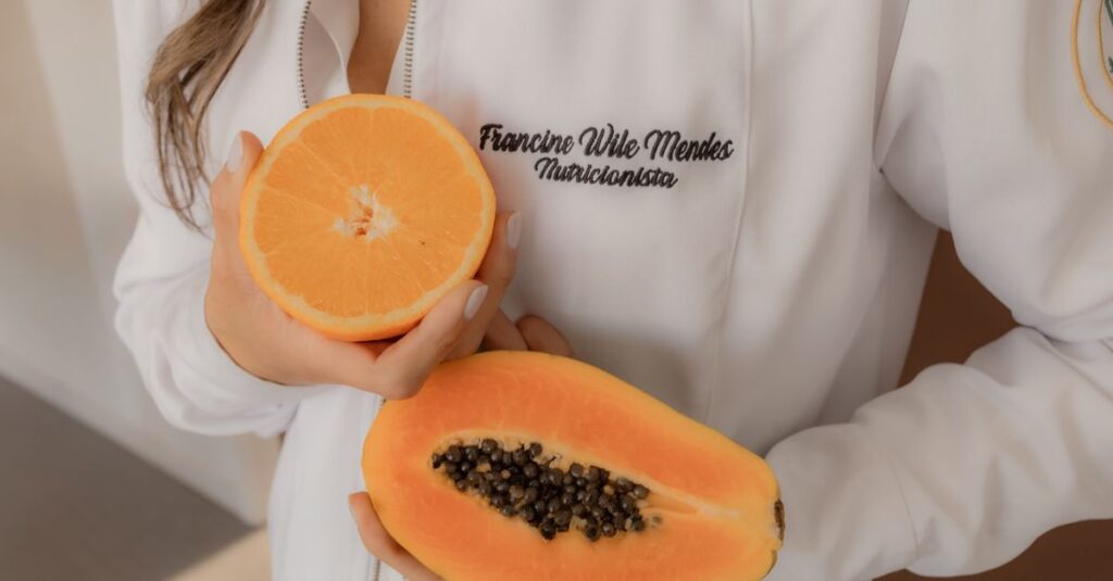 Como a Alimentação Afetiva Pode Transformar Seu Bem-Estar 2 A nutritionist holding fresh papaya and orange, highlighting healthy eating.