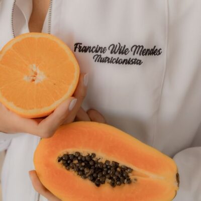 A nutritionist holding fresh papaya and orange, highlighting healthy eating.