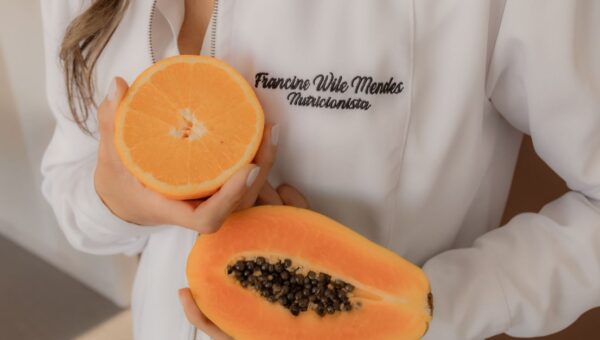 A nutritionist holding fresh papaya and orange, highlighting healthy eating.